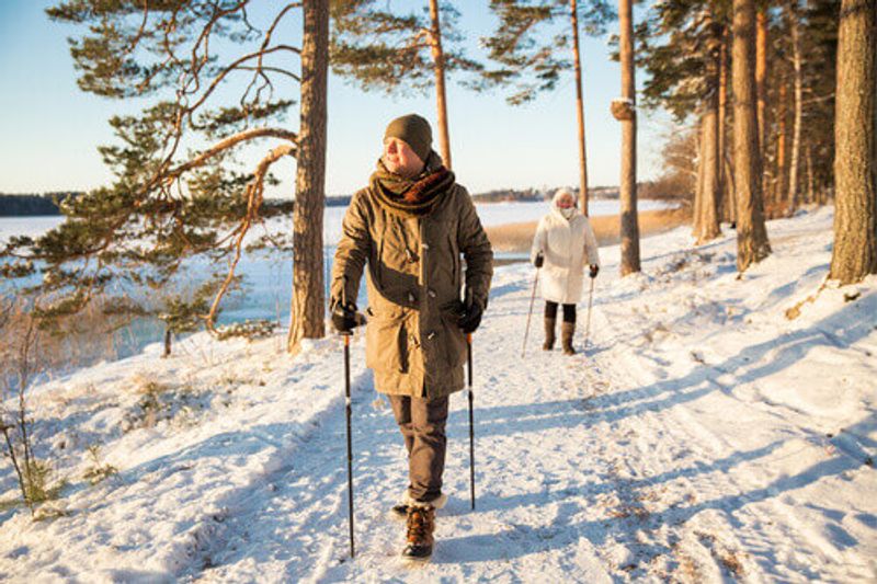 An adventurous man and woman walking in a snowy forested area in Finland.