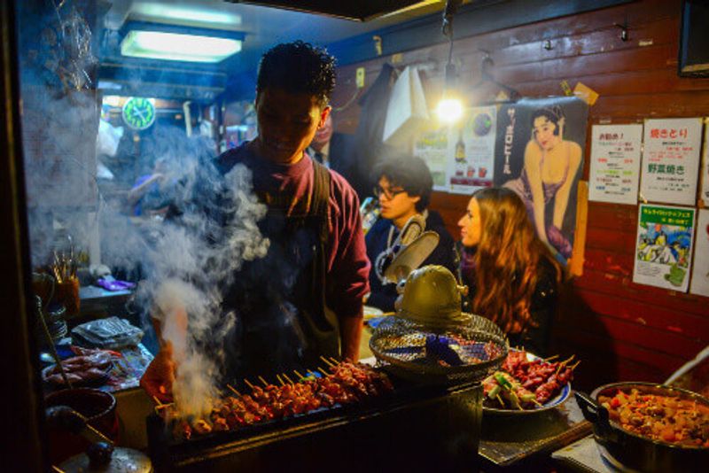 A tiny food stall in Omoide Yokocho, Shinjuku District, where a Japanese man grills tasty BBQ for customers.