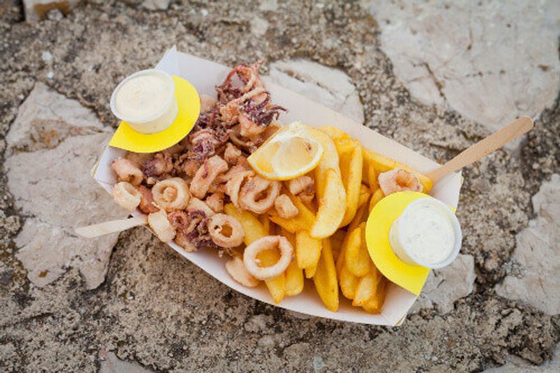 Deep fried squid with chips and white mayo sauce, a traditional seaside fast food during holidays in Krk.