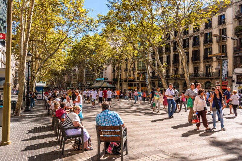 People gather in La Rambla street with the Liceu Theatre visible.