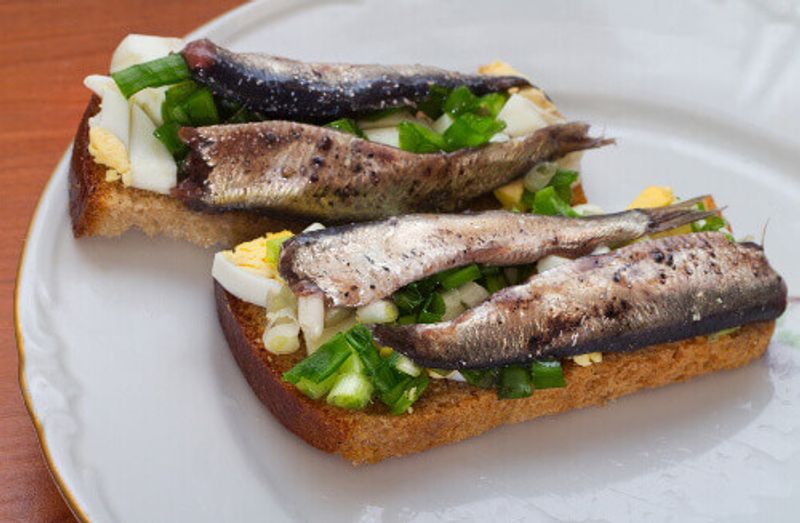 The Estonian national Sprat sandwich on plate with egg and pickles.