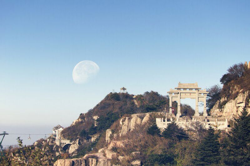 A waning moon over the mountains of Tai Shan or Mount Tai, and Peng Yuan Gate in the Shandong Province, China.