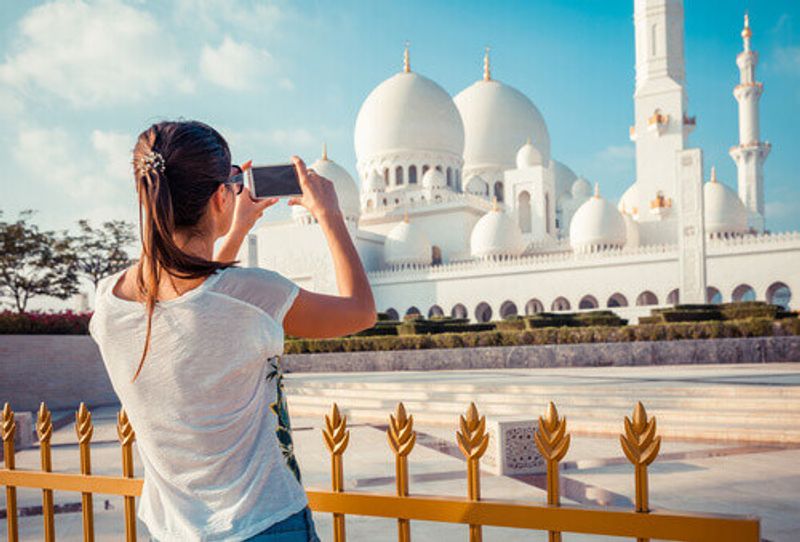 Woman taking photos at the Sheikh Zayed Great white Mosque.