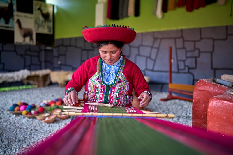 Peruvian woman from the town of Chinchero weaving traditional cloth made with alpaca animal hair