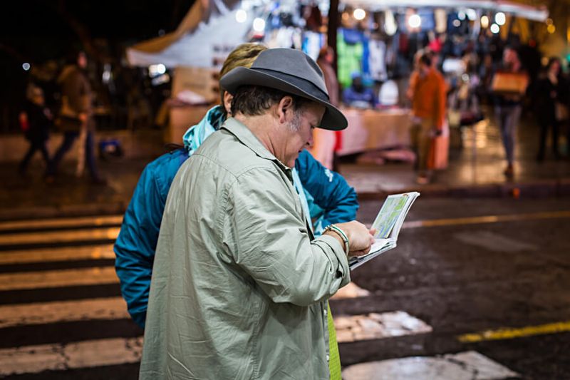 A man helps a tourist find a location on a map in Seville.