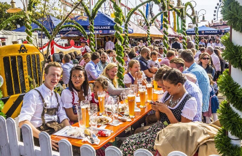 People dressed in traditional costumes sitting in the beer garden during Oktoberfest.