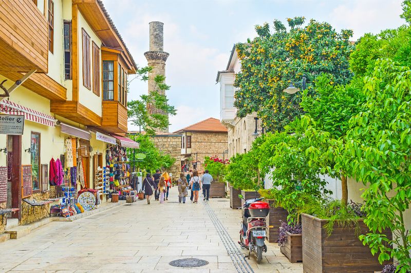 The Kesik Minare Cami is in the distance as tourists and locals walk down a busy street.