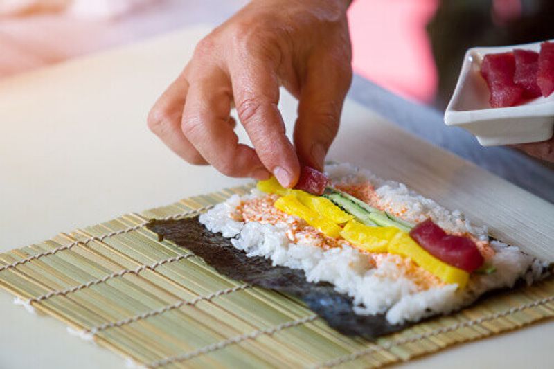 Raw fish and white rice is lined on seaweed.