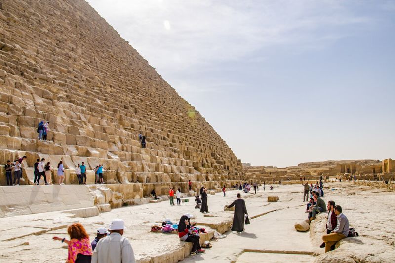 Tourists resting at the bottom of Cheope Pyramid in Giza