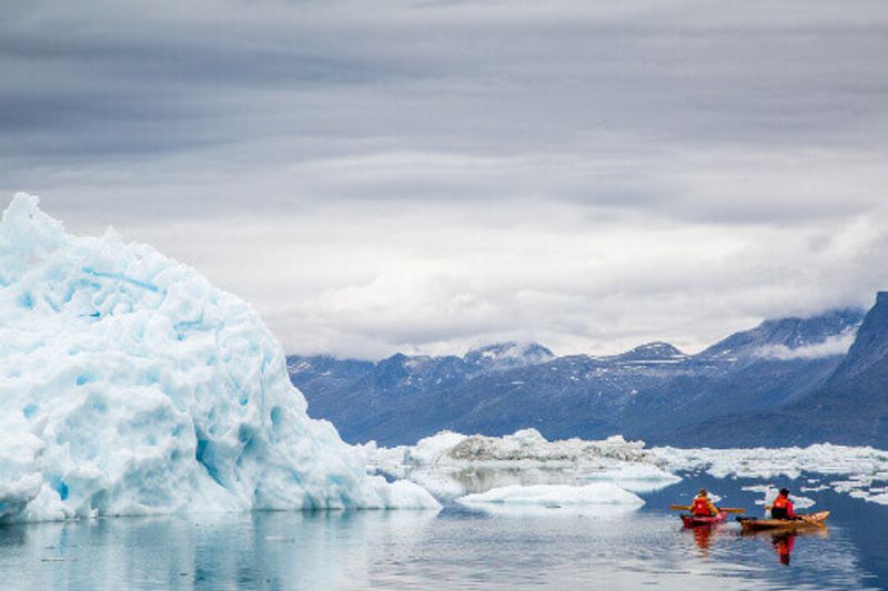 Tourists kayaking beside a huge iceberg in Nuuk.