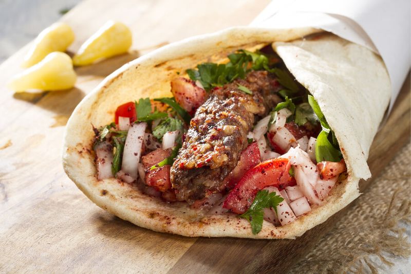 A local favoutie, Turkish Adana Kebab is seved on a wrap served with yoghurt and peppers.