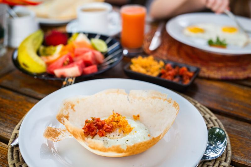 Traditional Sri Lankan breakfast of fruit and egg hoppers.