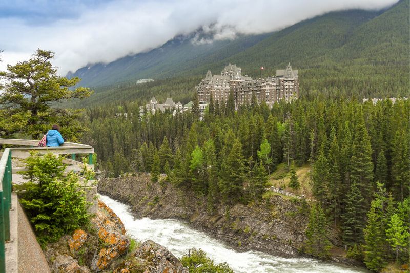 A visitor at a lookout point viewing the Bow River and Banff Fairmont Springs Hotel.