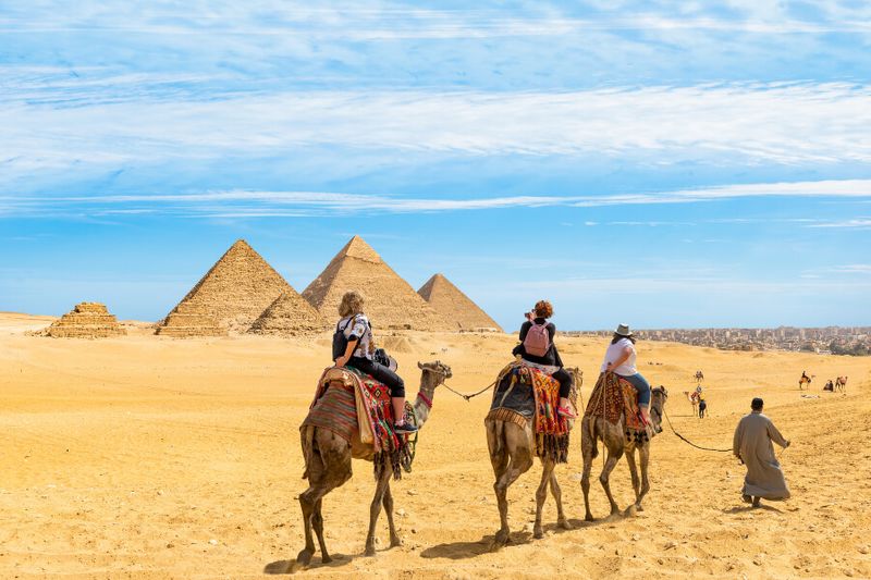 Female tourists on a camel ride near the Great Pyramids of Giza.