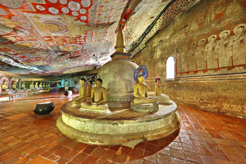 Golden Buddhist statues meditating in the historical Dambulla Cave.