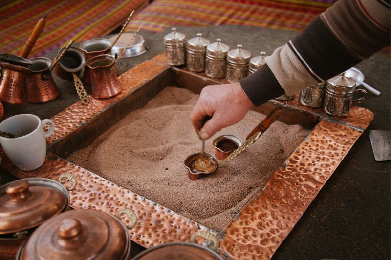 Traditional Turkish coffee's are being cooked in the sand.