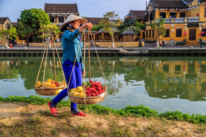 A Vietnamese woman selling colourful fruit along the river bank in Hoi An