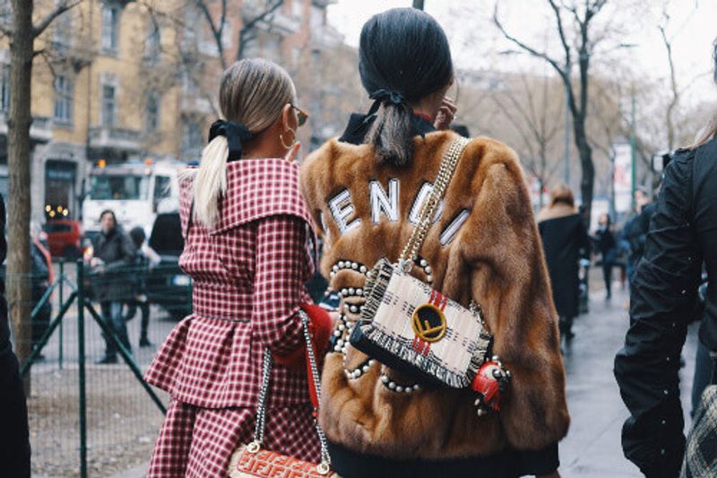 Fashionable women wearing Fendi clothing at Milan Fashion Week.