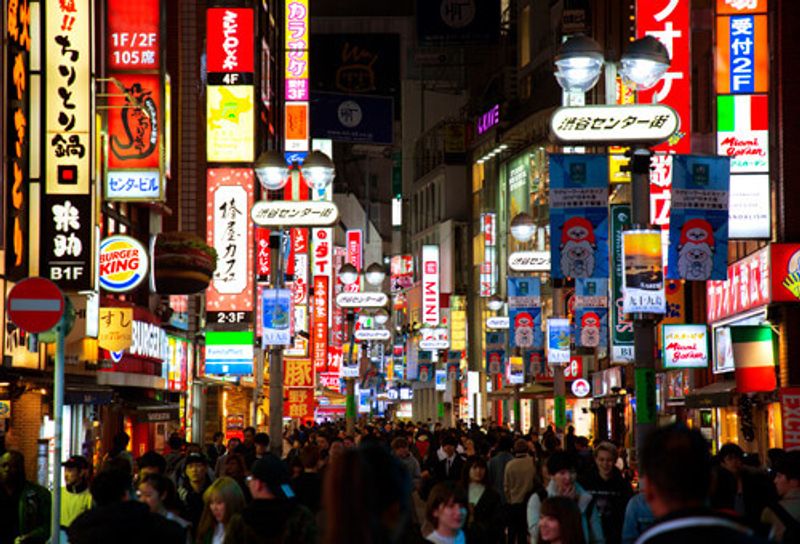 Shibuya at night with visitors passing through.