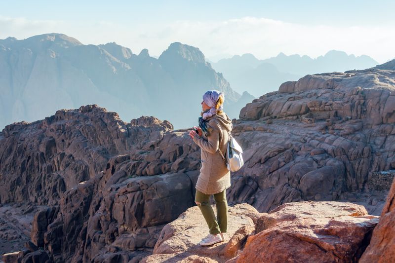 A female hiker stands on the edge of a cliff in the Sinai Mountains.