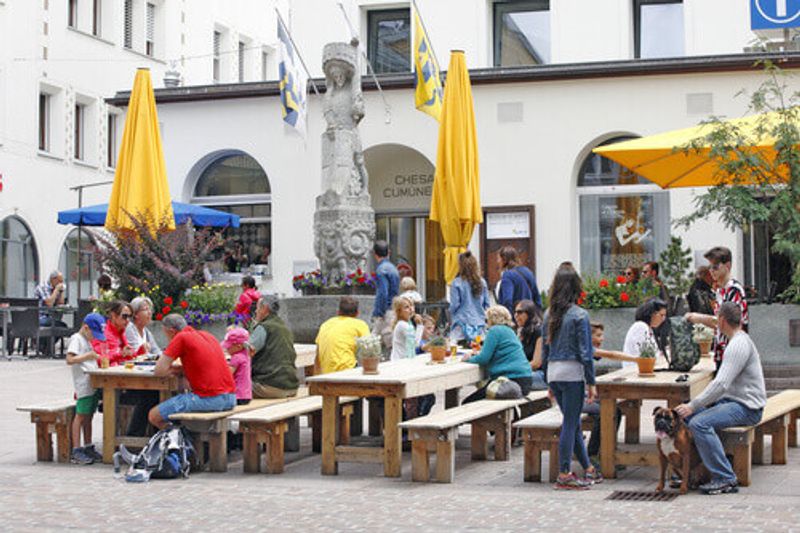 A lot of tourists gather on a small square in front of the Municipal House in St Moritz, Switzerland.