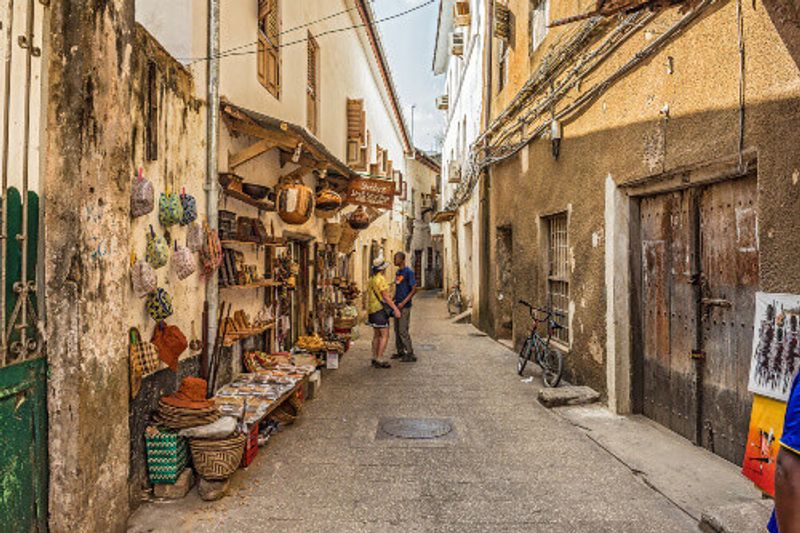 Tourists explore a typical narrow street in Stone Town, an old part of Zanzibar City.