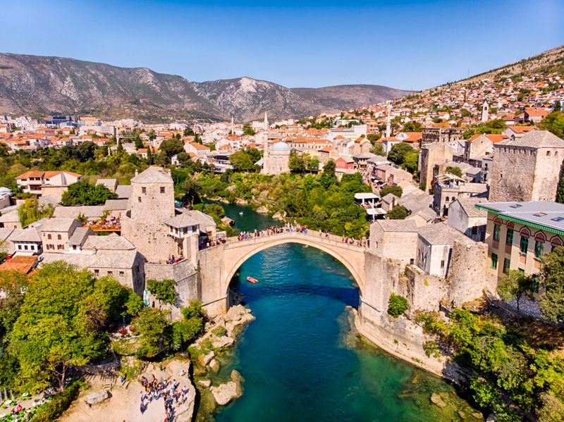 Riverside view of Mostar with traditional buildings and bridge in Bosnia and Herzegovina
