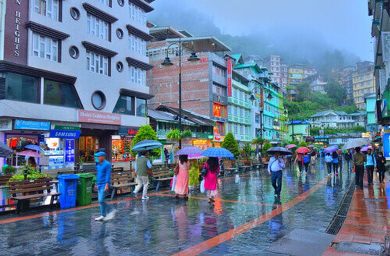 People walking in the MG Marg street carrying umbrellas in the rain in Gangtok, India.