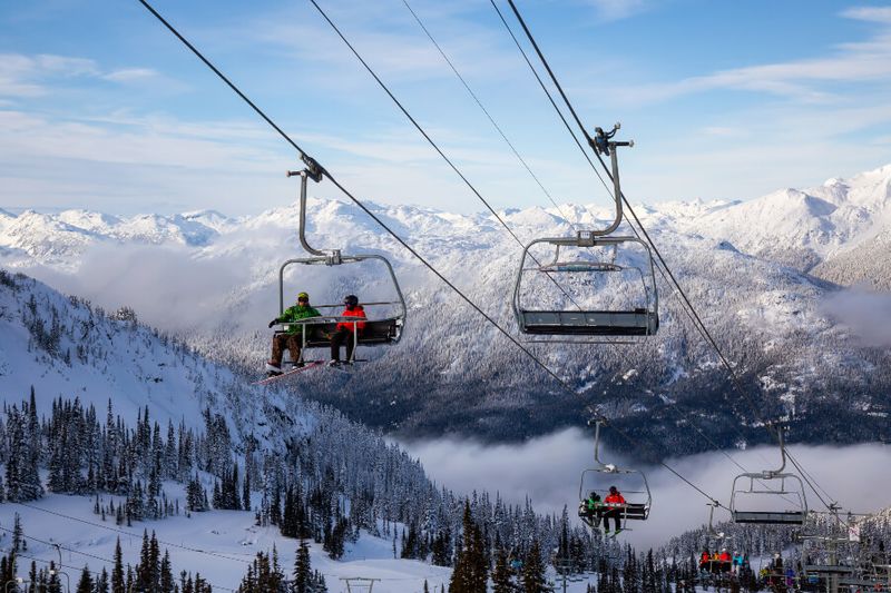 People going up the ski mountain on a chairlift on a sunny winter day