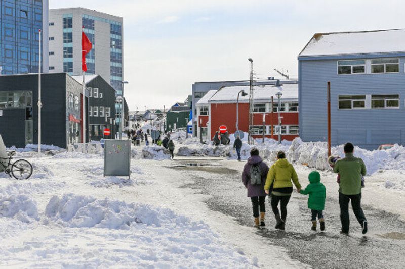 Central pedestrian street with modern buildings and shops in Nuuk.