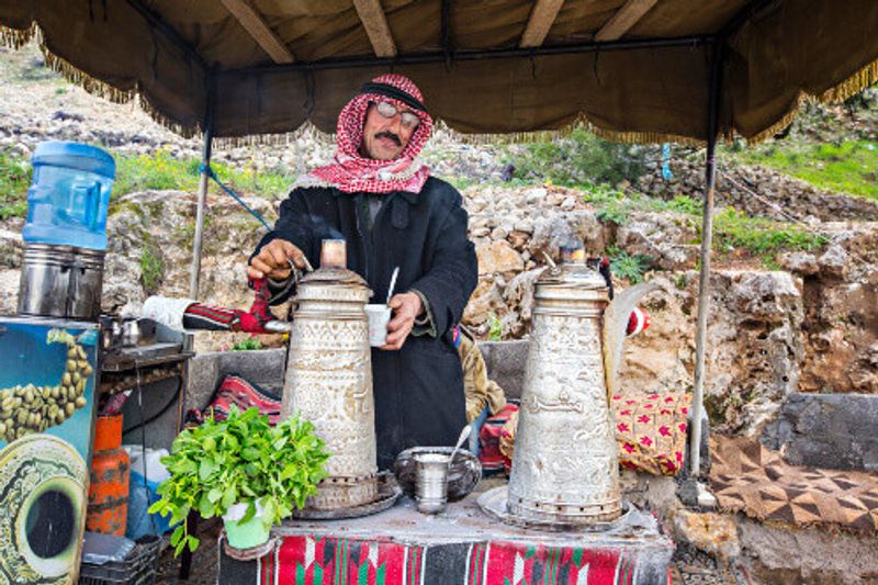 Bedouin man, traditionally dressed, preparing Bedouin mint tea in Ajloun.