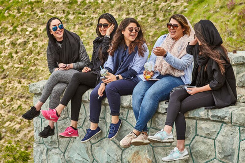 Group of Iranian women sitting and laughing on a friendly conversation.
