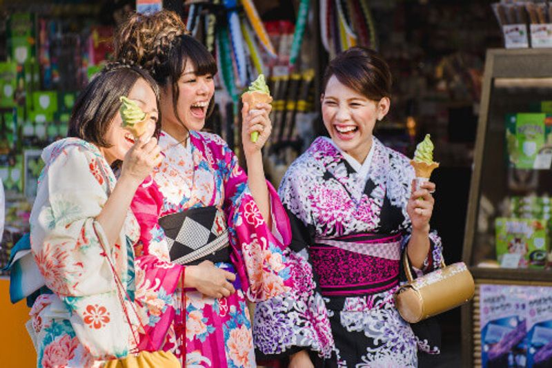 Japanese women with ice-cream, wear traditional Kimono on the streets of Kyoto, Japan.