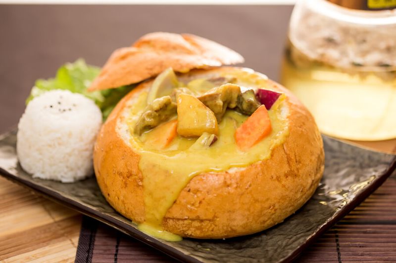 Famous bunny chow bread with curry inside the buns and rice on the side.