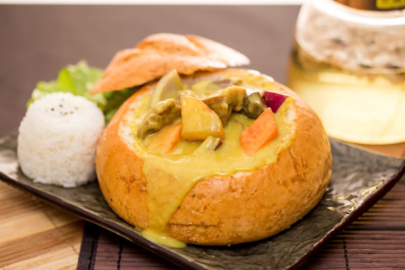 Famous bunny chow bread with curry inside the buns and rice on the side.