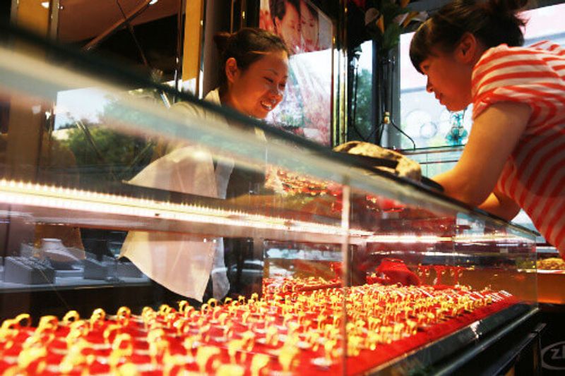 In Zhou Liu Fu jewelry shop, a salesperson talks to a person interested in purchasing gold in Beijing, China.