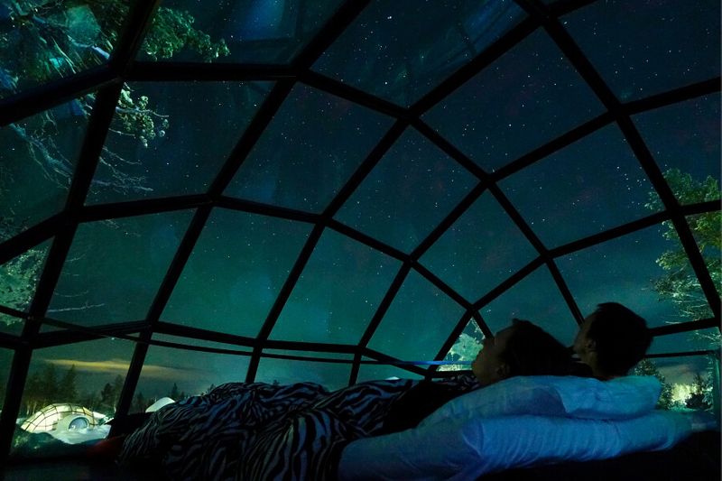 A couple admiring the aurora borealis at the glass igloo in Kakslauttanen Arctic Resort