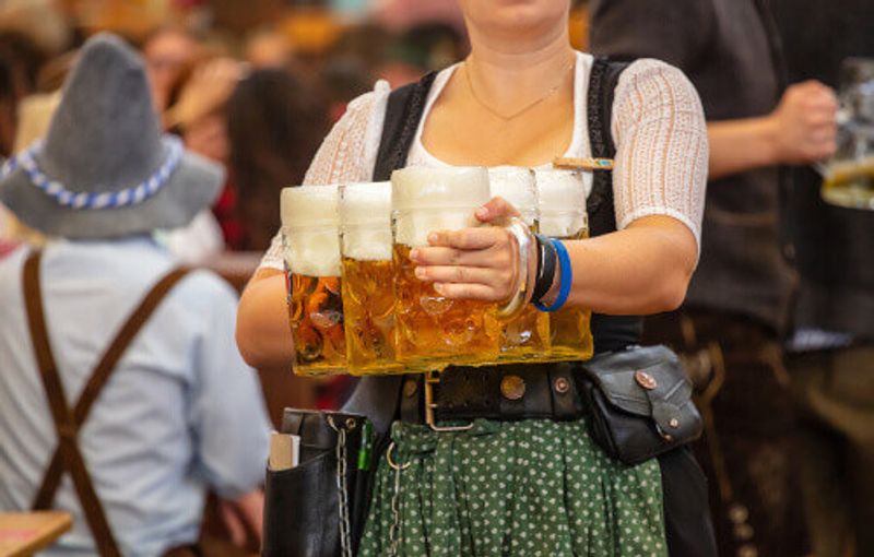Waitress with traditional costume professionally holding beers during Oktoberfest.
