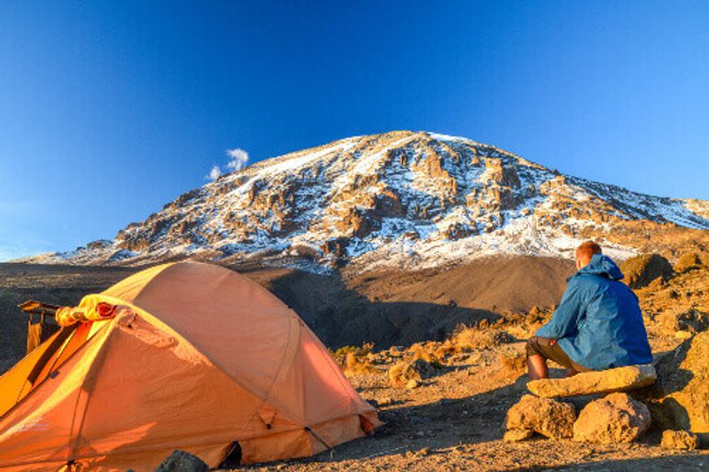 Tourist in Kibo with Uhuru Peak, the highest mountain in Africa, at Mount Kilimanjaro.