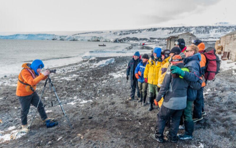 A group of people stop to take a photo in front of Scott's Hut in Antarctica.