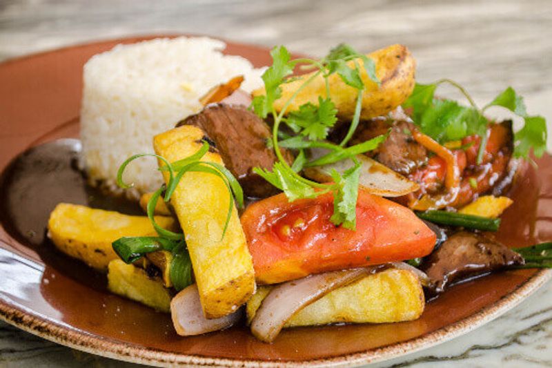 Lomo Saltado, a popular Chifa or Peruvian - Chinese stir fry dish combining marinated beef sirloin, onions, tomatoes and french fries, served with white rice in Peru