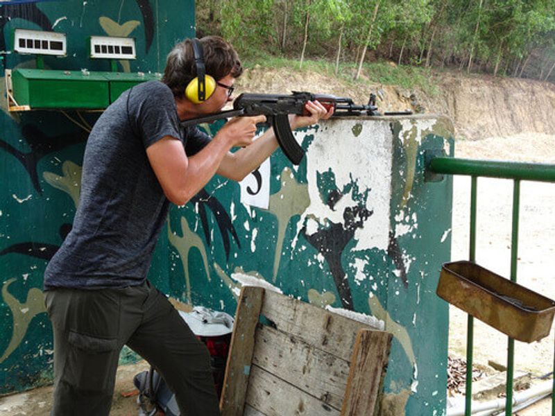 Tourist shooting an AK 47 on a shooting range in the Cu Chi Tunnels in Vietnam.