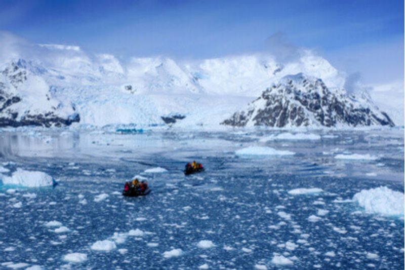 Two Zodiac boats cruising through icy water in Antarctica.
