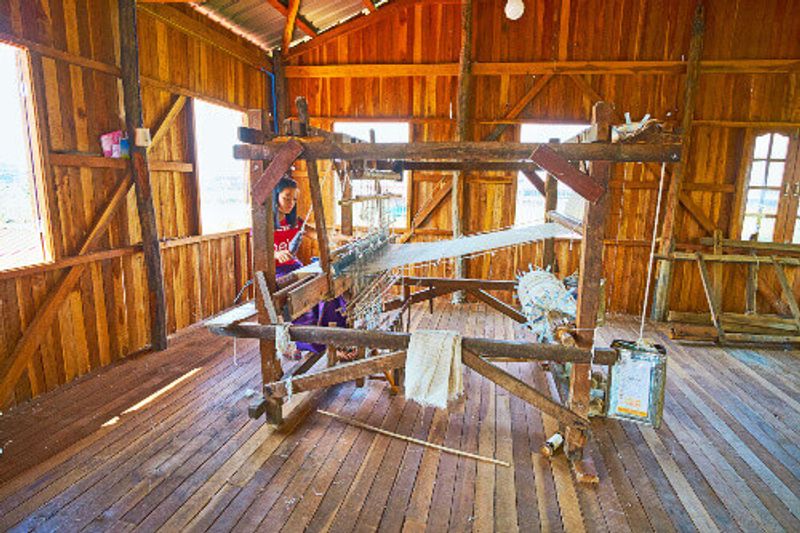 A young girl produces a lotus fabric, working on the old hand loom in a weaving workshop.