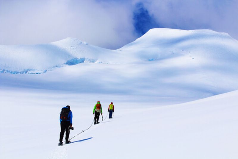 People hike through the cold snow in Antarctica.