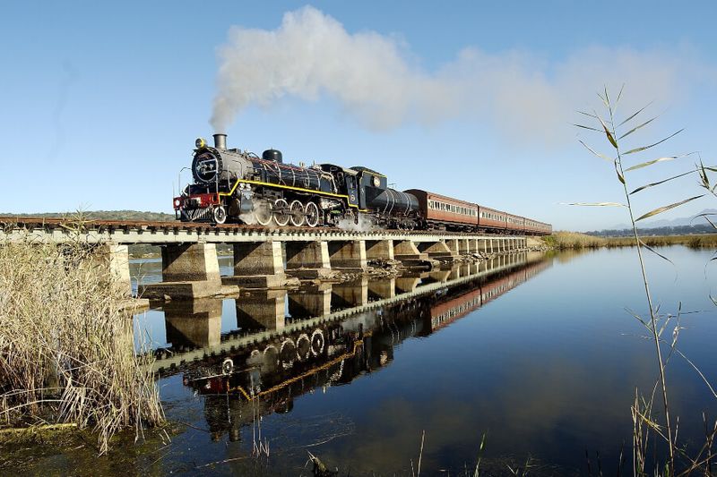 A vintage steam train on a bridge.