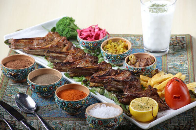 A Shashlik Kebab is plated alongside side dishes and sauces.