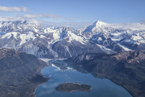 An aerial view of Lituya Bay with the Mt. Fairweather Range in the background on a sunny day.